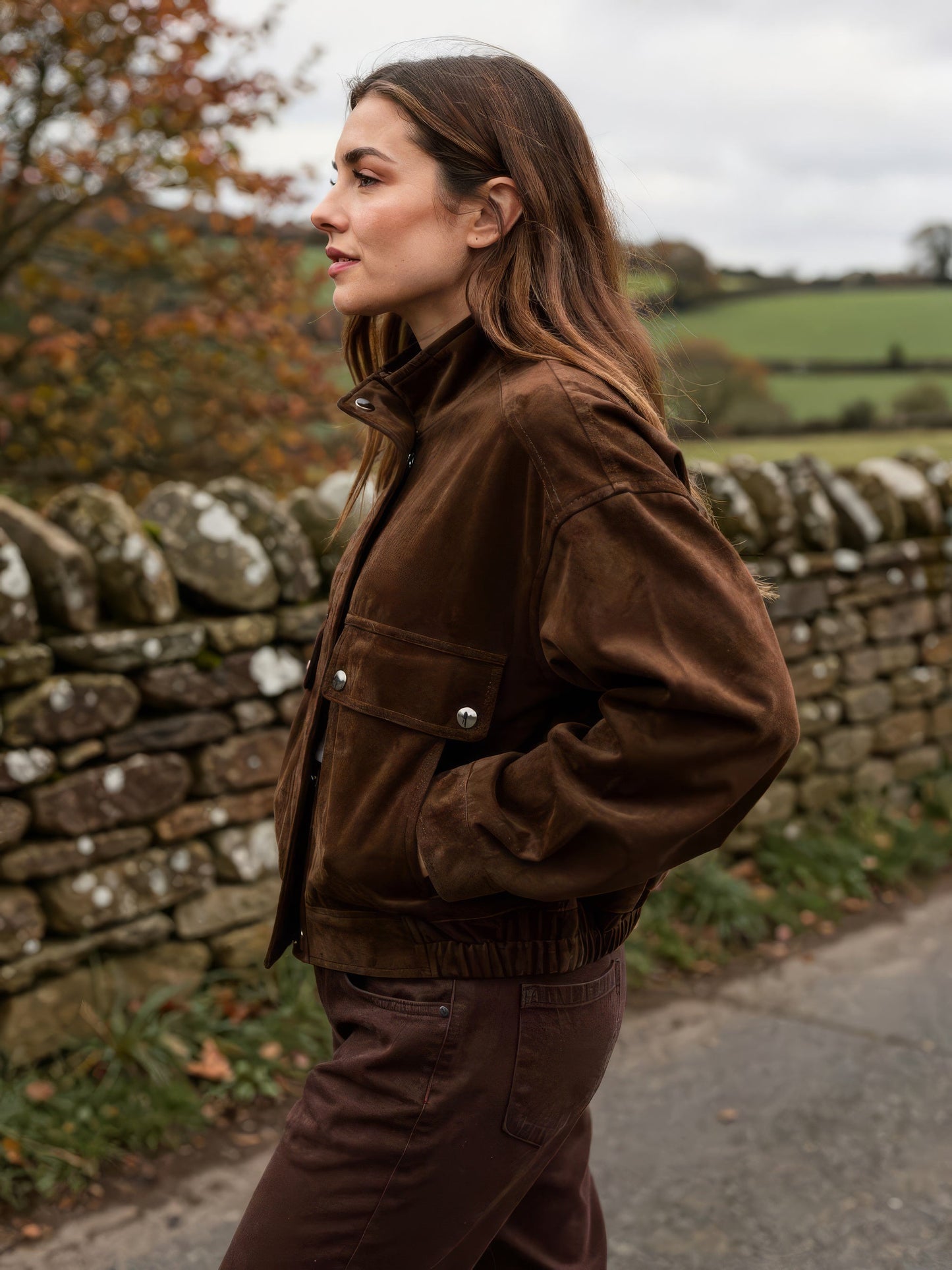 Suedette bomber jacket in coffee bean brown worn on an English country lane, side view