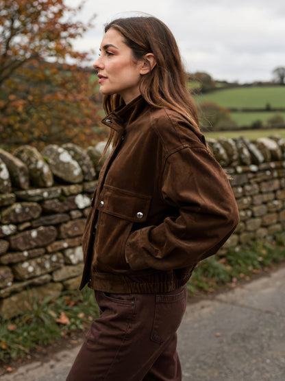 Suedette bomber jacket in coffee bean brown worn on an English country lane, side view