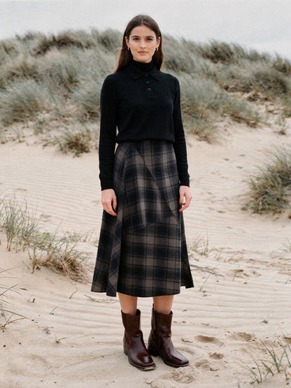 Tartan midi skirt in a brown and black shadow check, worn with a black roll-neck jumper on coastal dunes