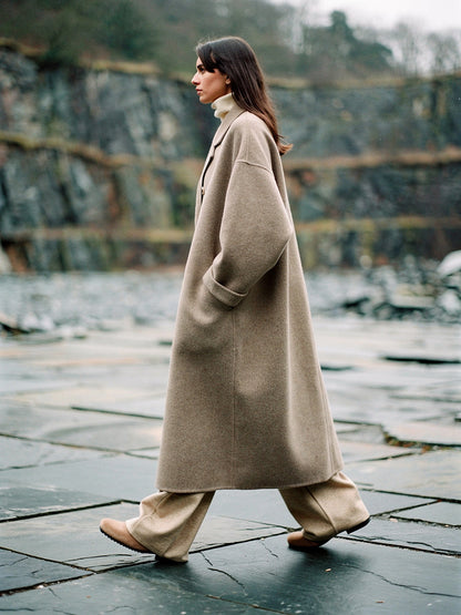 Oversized wool coat in Porcini seen in profile, dropped shoulders and wide straight sleeves