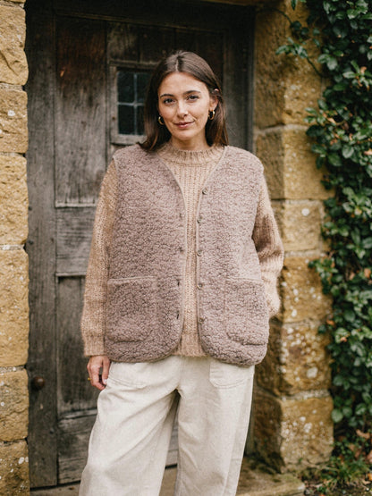 Mocha teddy gilet layered over an oatmeal jumper in a cottage porch