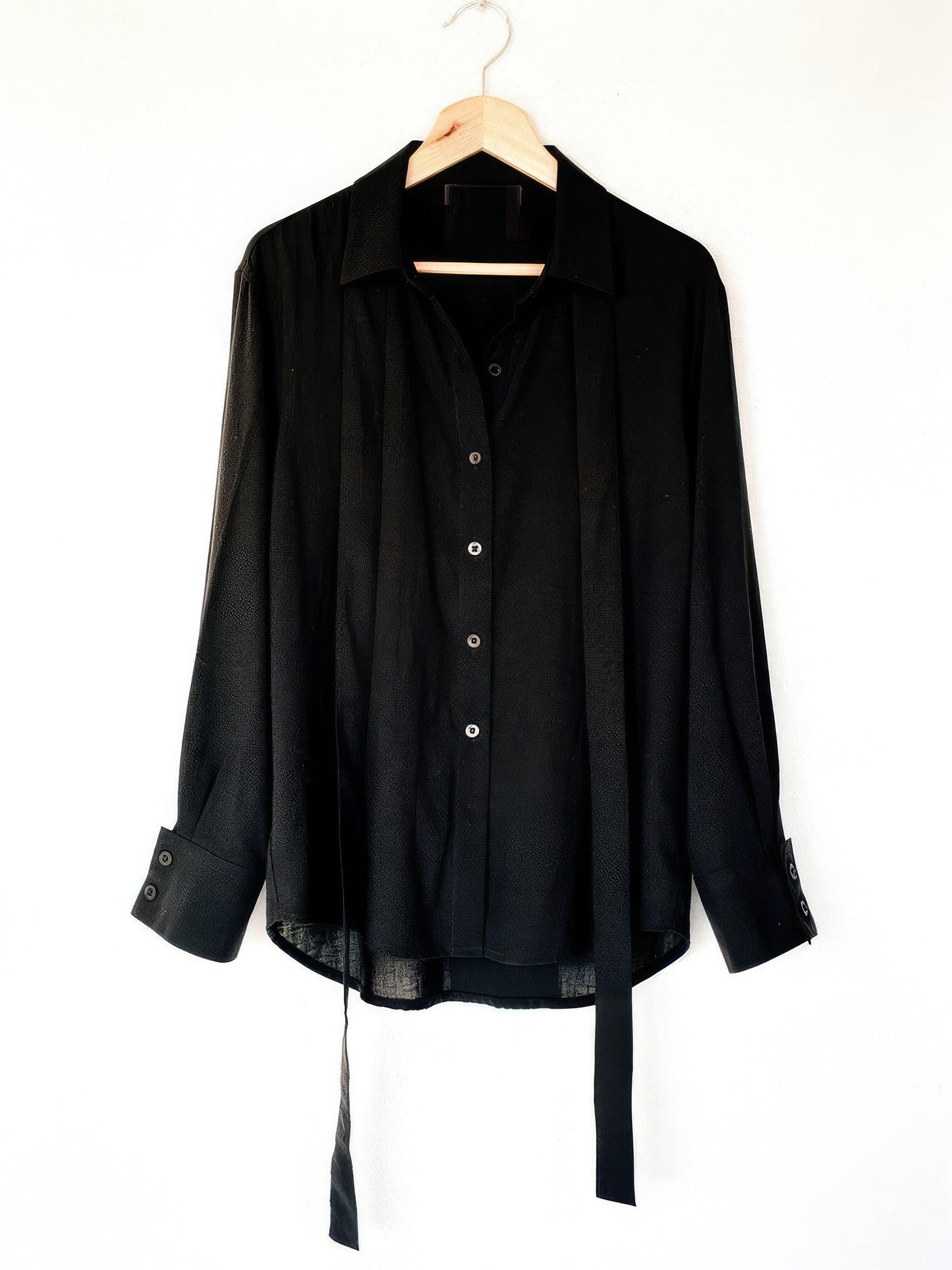 Black tie-waist blouse on a hanger, front view with deep buttoned cuffs