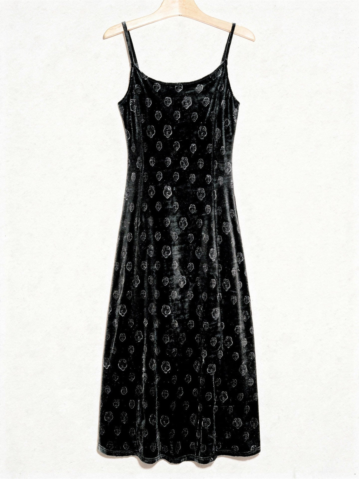 Velvet slip dress in black shown from the front on a plain wooden hanger