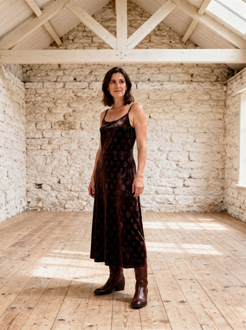 Brown velvet slip dress with a tonal rose motif, worn full length in a whitewashed sail loft