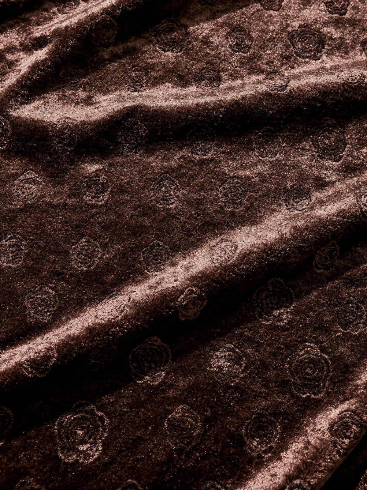 Close up of the rose motif worked into the brown velvet pile of the slip dress