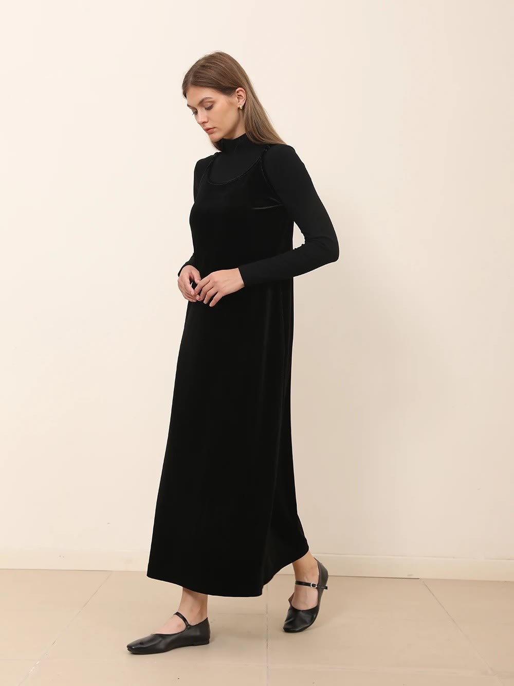 Velvet strap dress in black worn full length over a fine roll neck