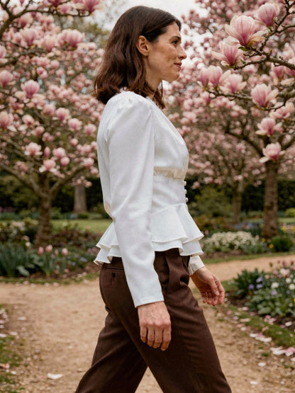 White peplum blouse worn in profile on a magnolia walk in spring