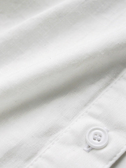 Close up of the soft cotton weave and one white four hole button of the white shirt