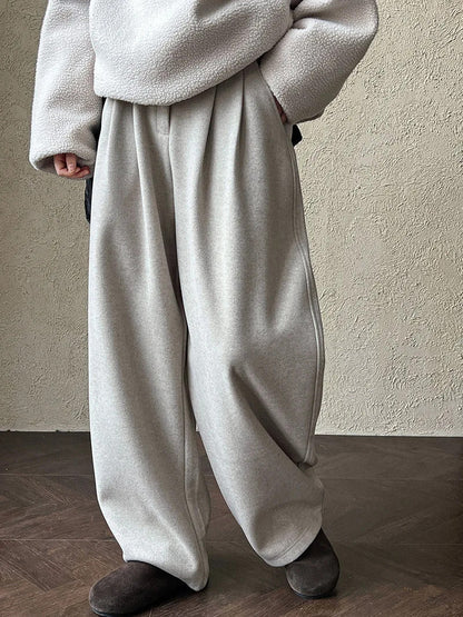 Putty wide-leg trousers worn front on, hands in the slanted side pockets
