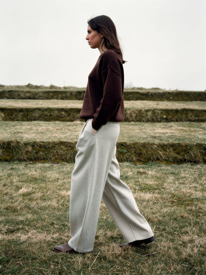 Side profile of putty wide-leg trousers showing the curved barrel leg and full length hem