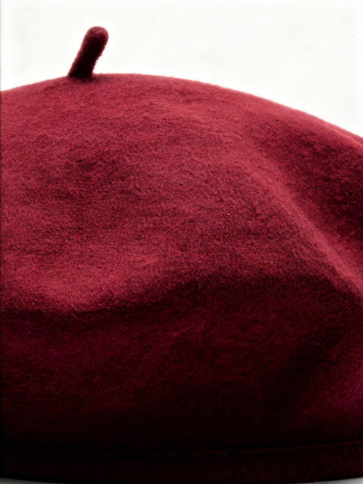 Close up of the milled wool felt and topknot of a womens beret hat