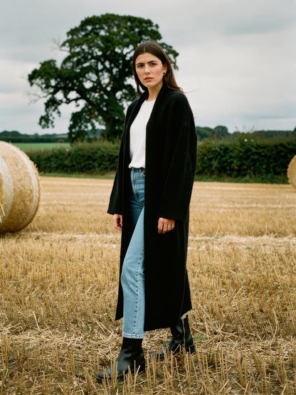 Womens black chunky knit coatigan worn open over jeans in an autumn field