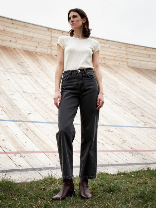 Black jeans in Faded Black worn with a cream knit at an outdoor timber velodrome