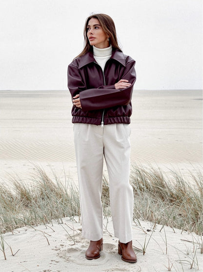 Womens burgundy faux leather jacket worn open over a cream roll neck