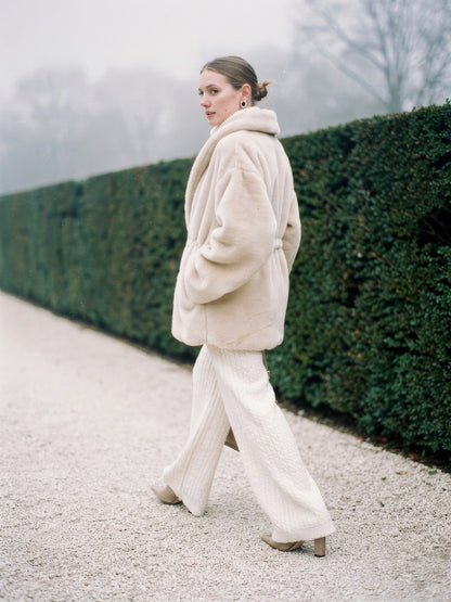 Womens cream faux fur coat worn walking, side view showing the cinched waist