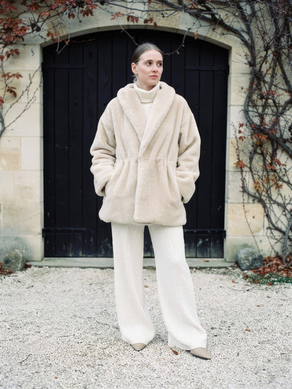 Womens plush faux fur coat with a shawl collar in cream, worn over cream knitwear, front view