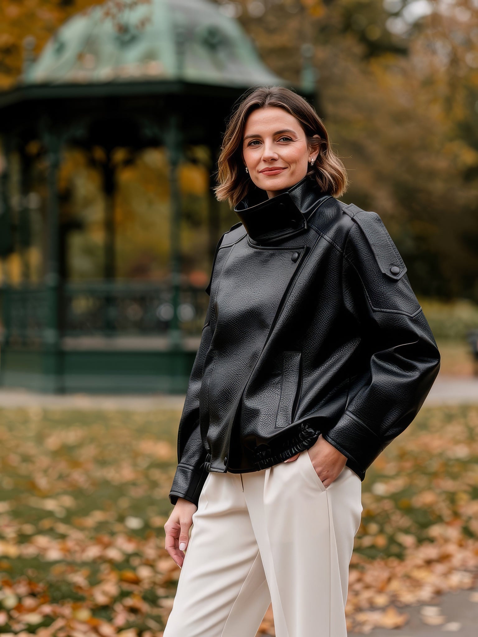 Womens black faux leather jacket, oversized fit with stand collar, worn in an autumn park