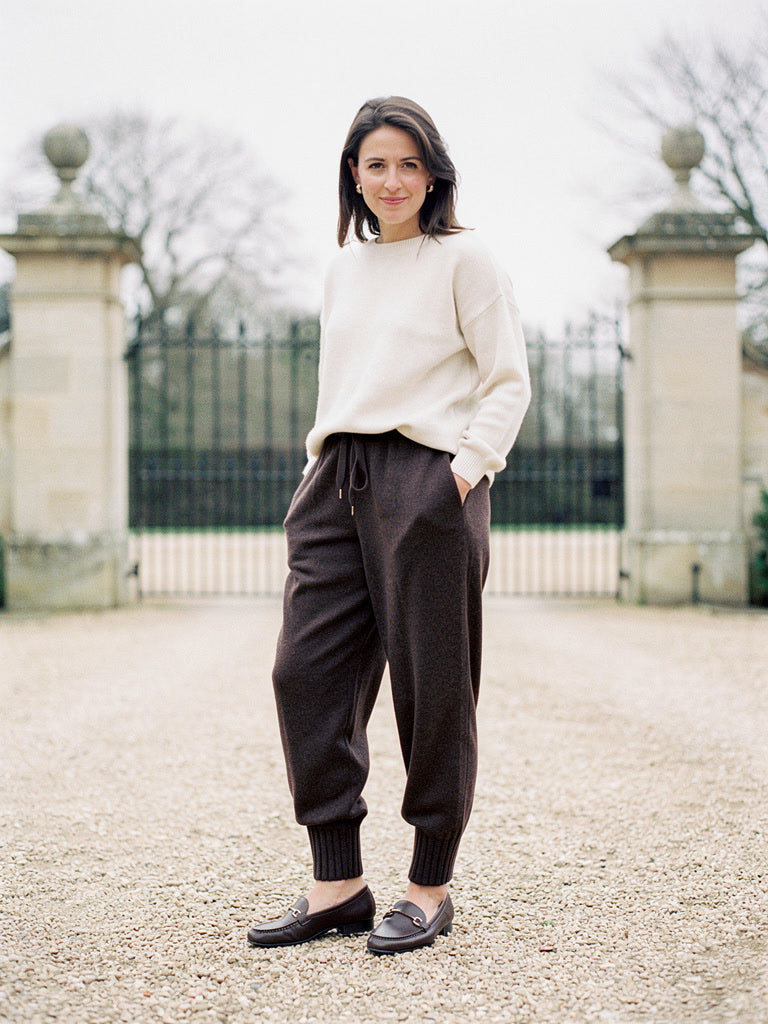 Womens knitted merino wool trousers in Dark Cocoa, worn with a cream jumper