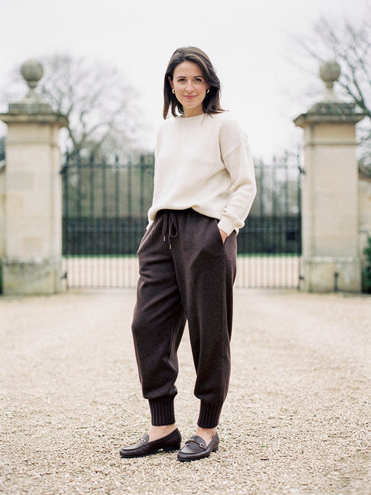 Womens knitted merino wool trousers in Dark Cocoa, worn with a cream jumper