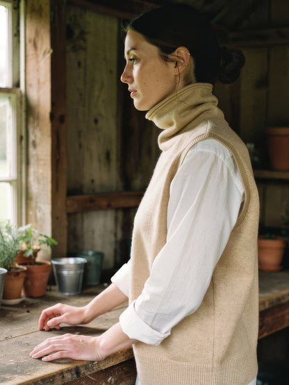 Woman wearing the Biscuit merino roll neck knitted vest over a white shirt