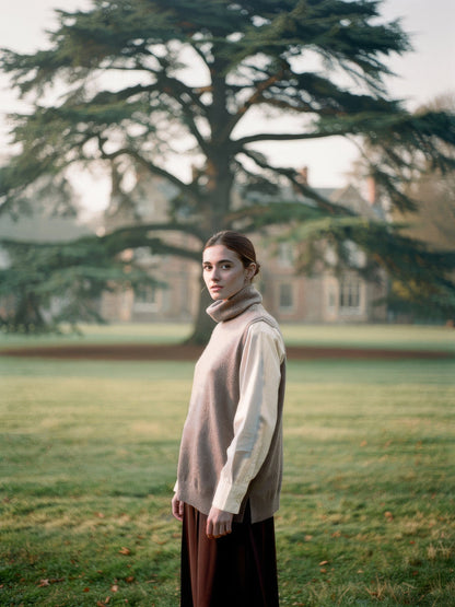 Woman wearing the Mushroom merino roll neck knitted vest over a shirt in English parkland