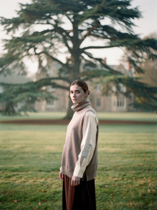 Woman wearing the Mushroom merino roll neck knitted vest over a shirt in English parkland