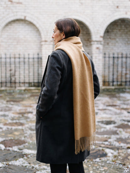 Wool scarf in Honey looped over the shoulders, seen from behind, fringe hanging down the back